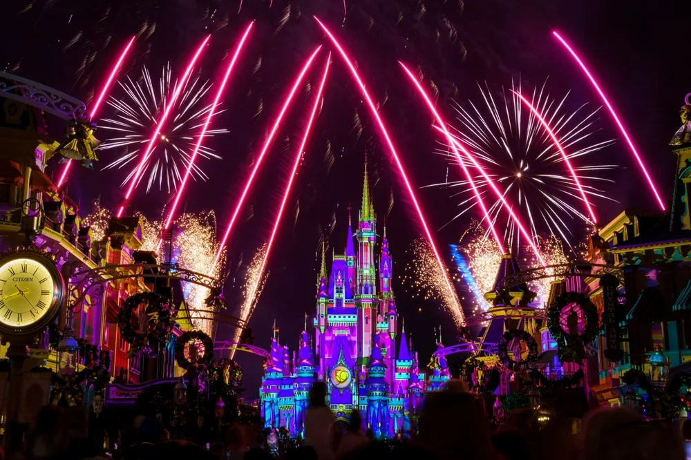 Disney World's Magic Kingdom park lit with fireworks and color over the castle for NYE in a guide showing the 8 best places to spend New Years in the USA