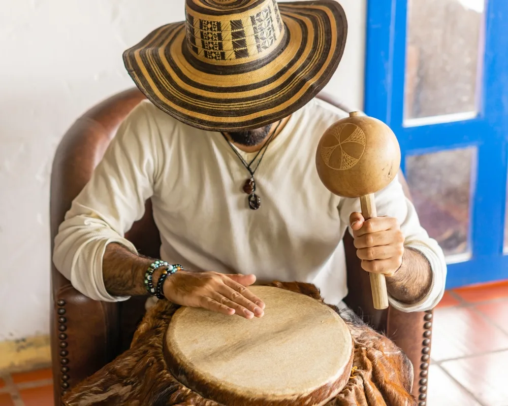 A man with drums and maracas while wearing a hat, playing a Cumbia music, the favorite of Salvadorians, an item on the list of facts about El Salvador.