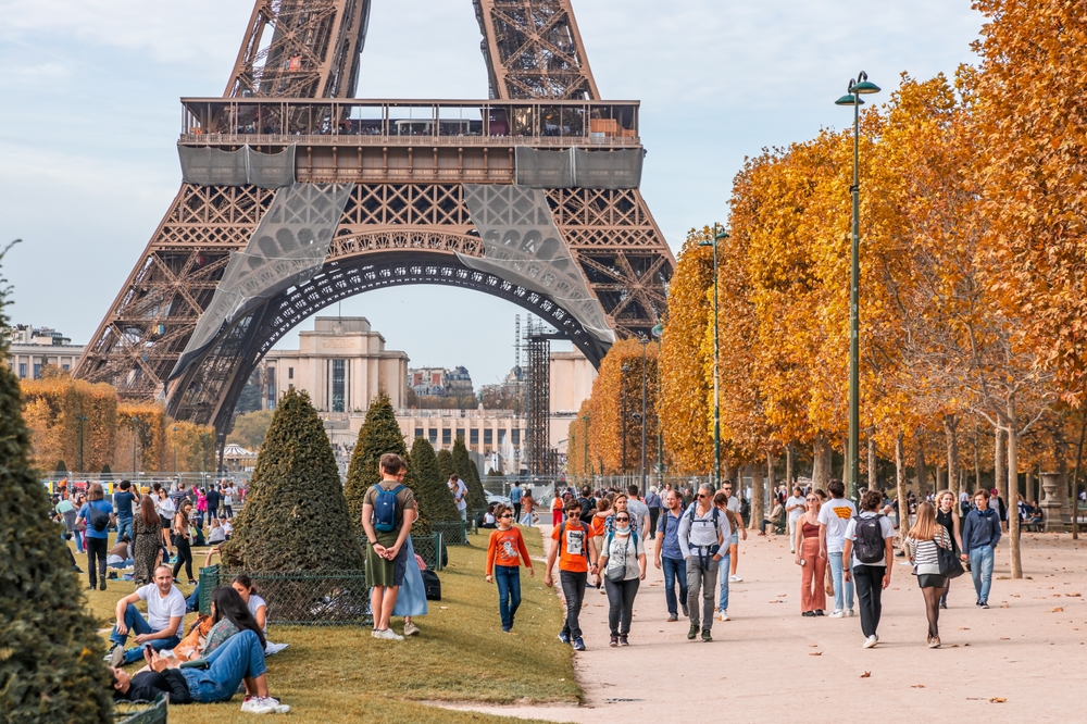 A large number of tourist gathering at the foot of the Eiffel Tower during Autumn.