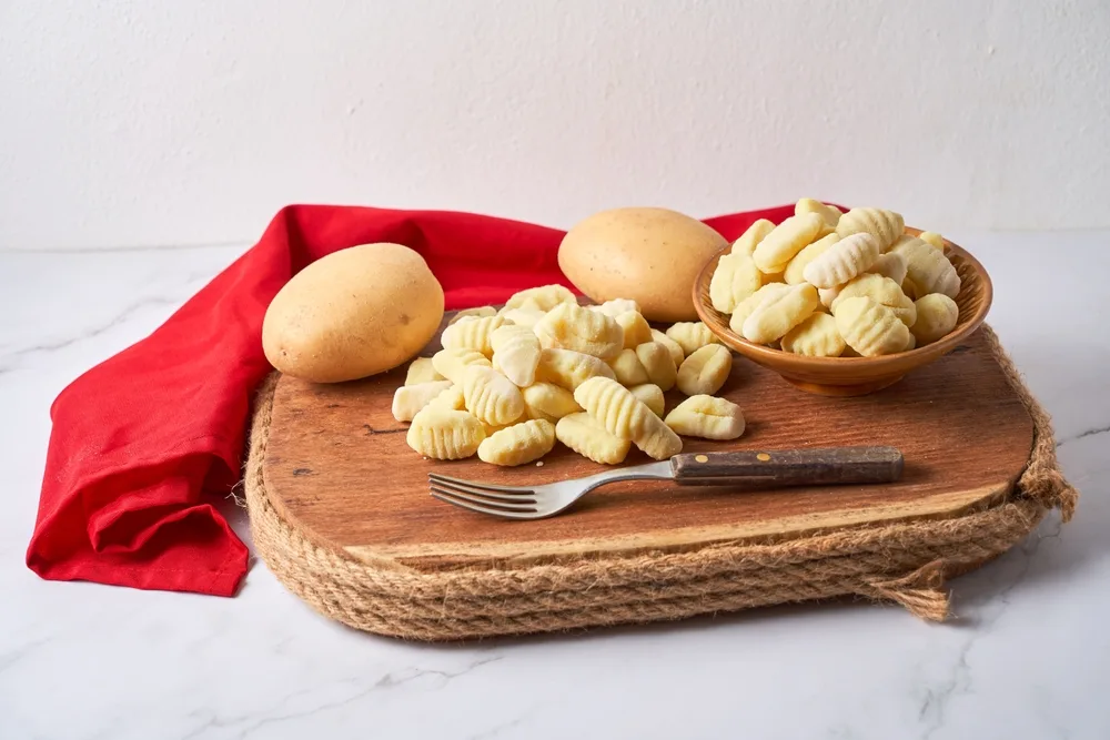 A food called Gnocchi made from potatoes prepared on a tray with fork together with whole potatoes, celebrating Gnocchi Day every 29th of the month is a tradition in South America.
