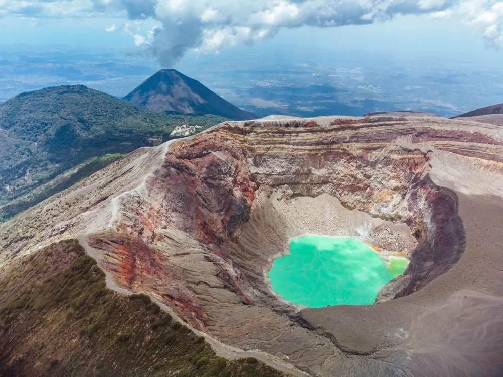 Aerial view of a volcano filled with a green substance on its crater, an area in El Salvador named as the land of volcanoes, one of the known facts about the country.
