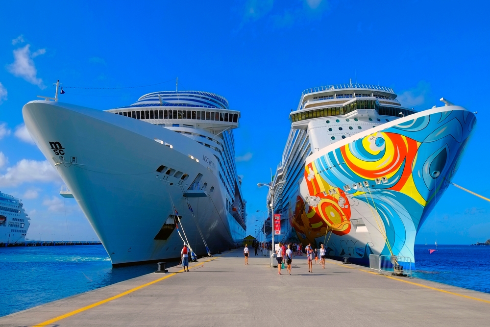 Two large cruise ship docked side-by-side on a pier.