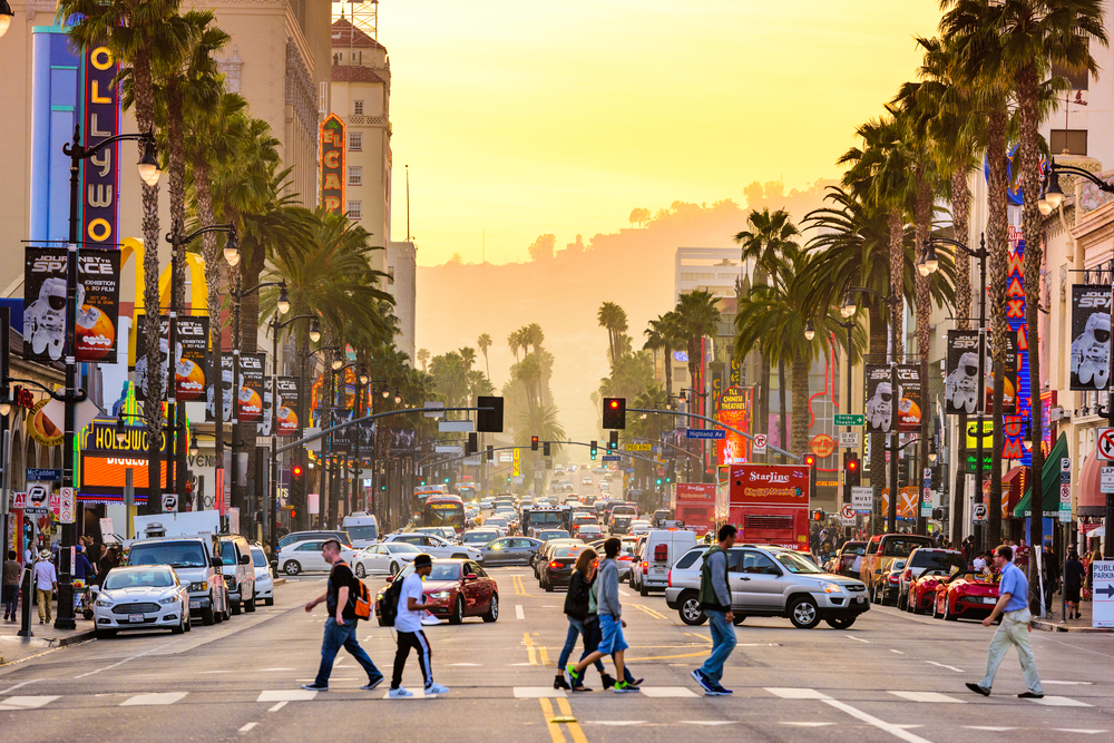 Hollywood Boulevard at dusk with tourists walking across the street in one of the best summer vacation ideas in the US