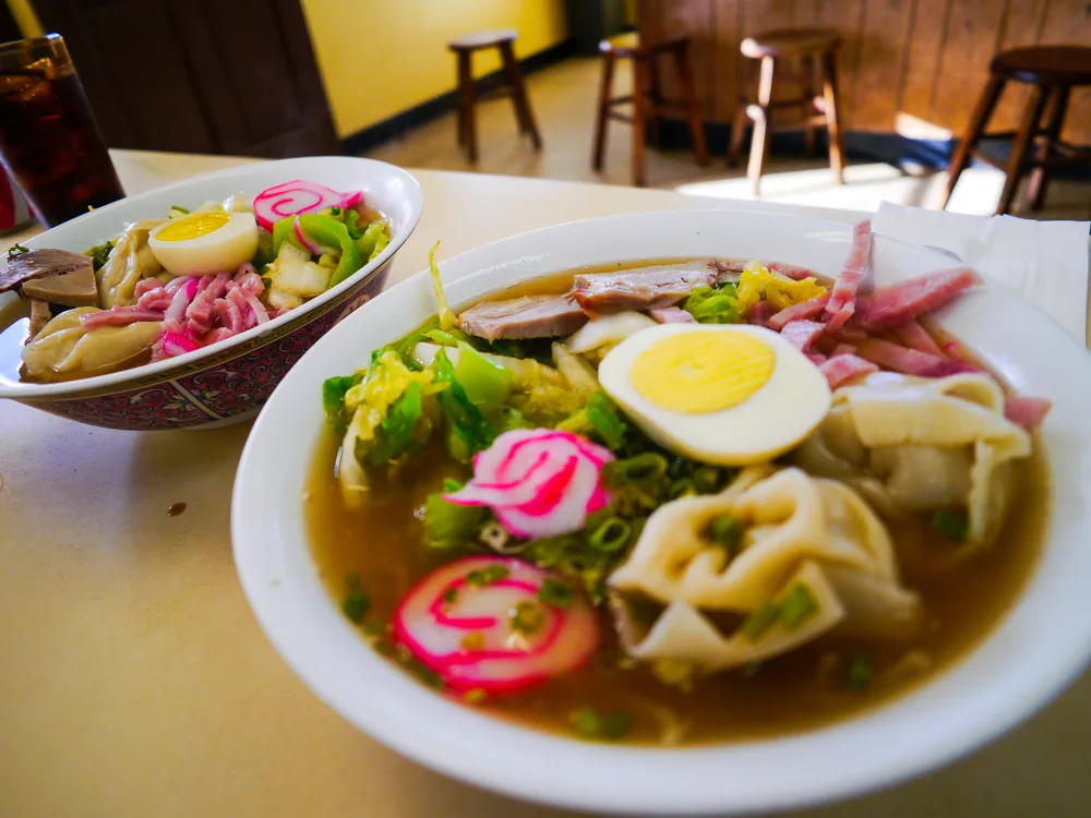 A bowl of saimin with Spam containing dumplings, fish cakes, Spam, and noddles with radishes for a guide covering why is SPAM so popular in Hawaii?