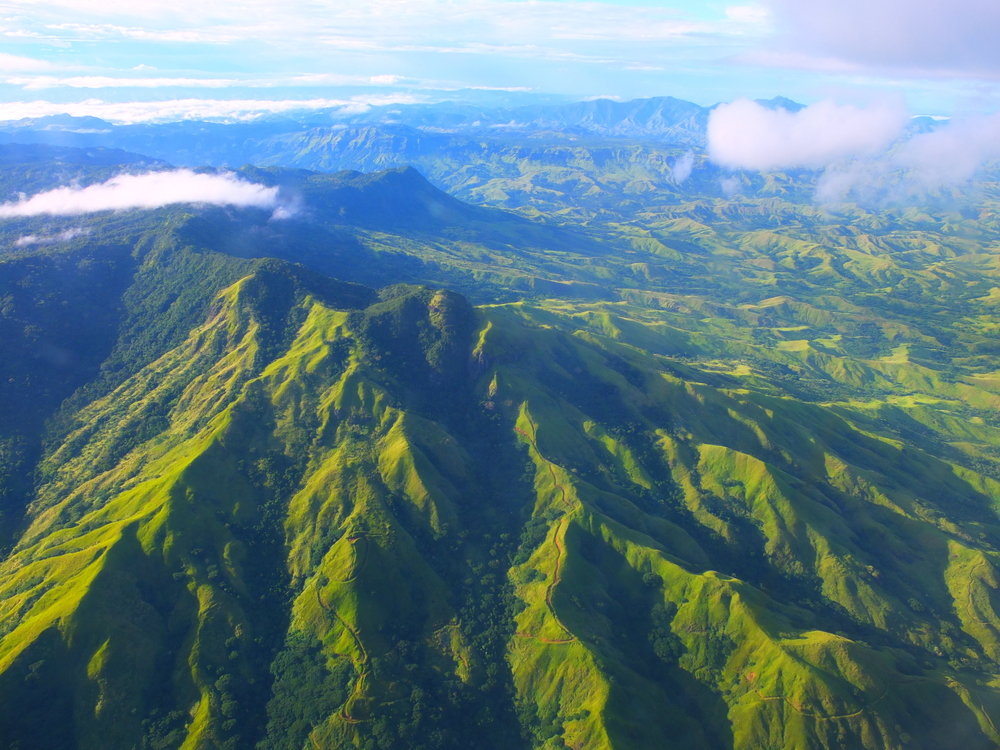 Rugged mountains in Fiji covered in greenery with clouds hanging low for a section answering how long is a direct flight to Fiji