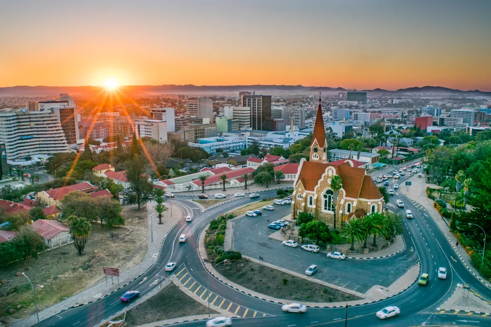 Aerial view of a city in Windhoek, one of the best areas to stay in Namibia, an old church is at the center of the roundabout and the rest of the city is seen during sunset.