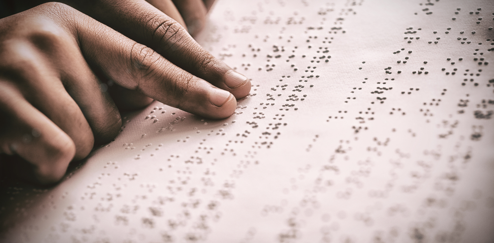 A person reading text through braille. 