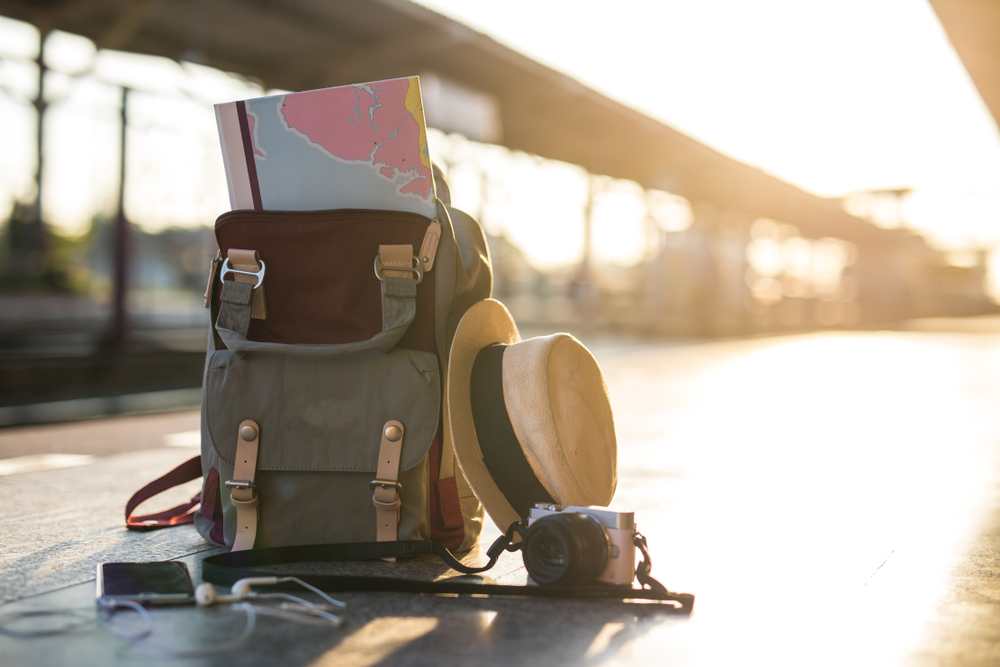 A backpack with a hat and a camera during sunset, packed for an Alaskan cruise.