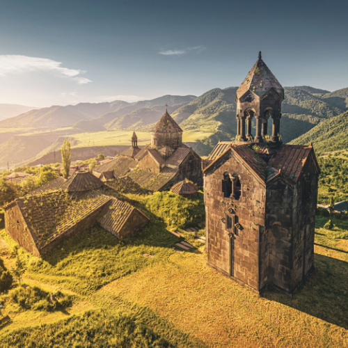 an old church located on a valley of a mountainous area with green fields, seen during the best time to visit Armenia.