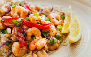A shrimp dish with little rice and lime on the side, prepare on a plate.