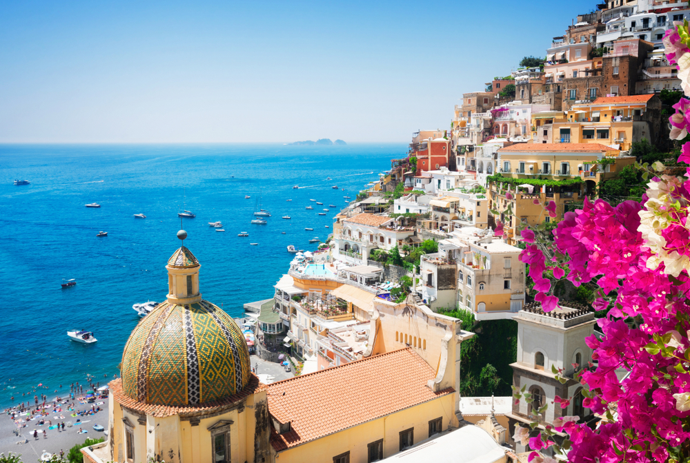 A hillside by the sea in Positano on the Amalfi Coast during spring with flowers in bloom on a clear, beautiful day depicts why this is one of Italy's best cities to visit