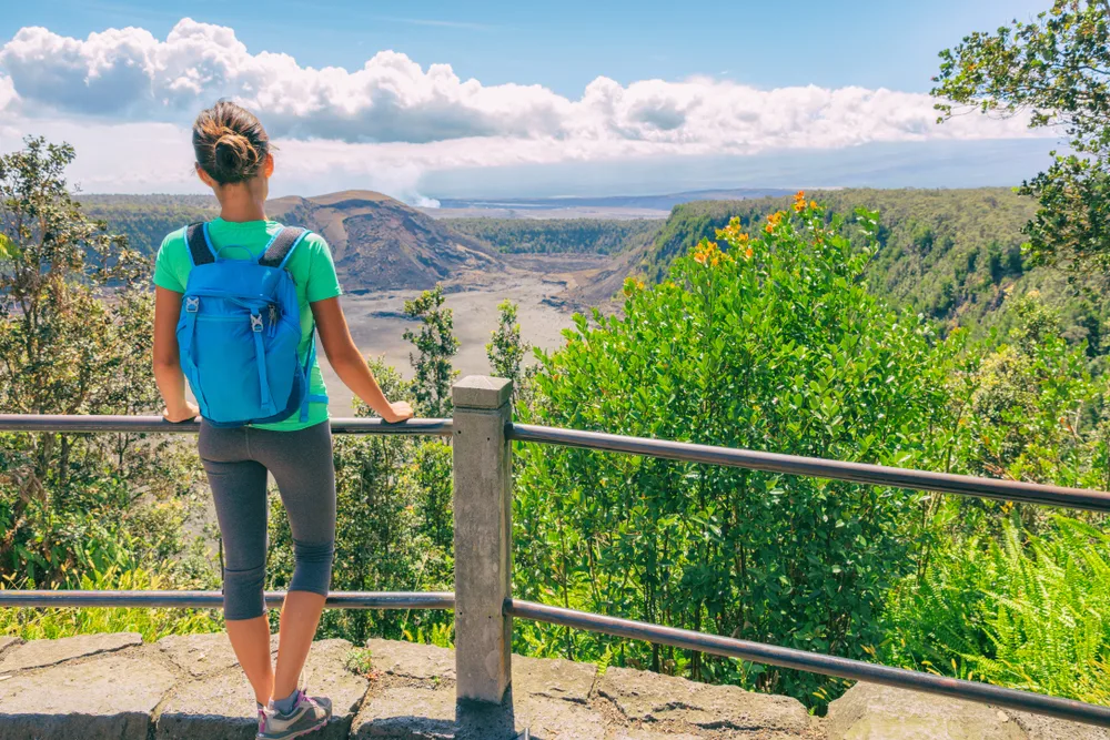 Woman in athletic pants standing at a railing overlooking the crater at Kilauea