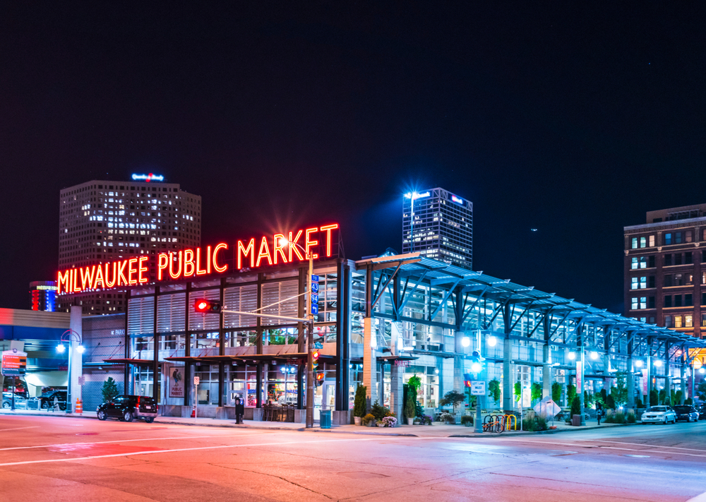 For a guide to whether or not Milwaukee is safe to visit, a night view of the Milwaukee Public Market lit up with neon signs
