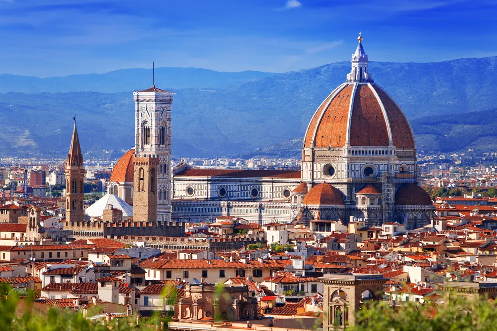 Aerial view of the Florence Cathedral dome and tower with mountains behind to show one of Italy's best cities to visit