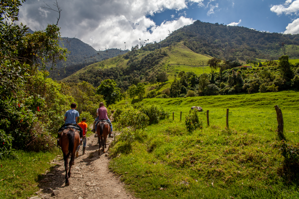 Tourist riding horses through the Cocora Valley Trail in Colombia for a guide titled Is Colombia Safe to Visit