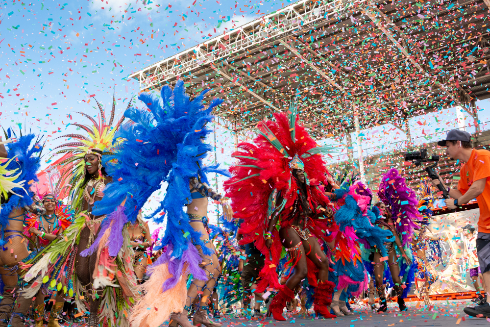 Street dancers wearing vibrant clothes with confetti flying all around, a festival on one of the best Caribbeans islands to visit.