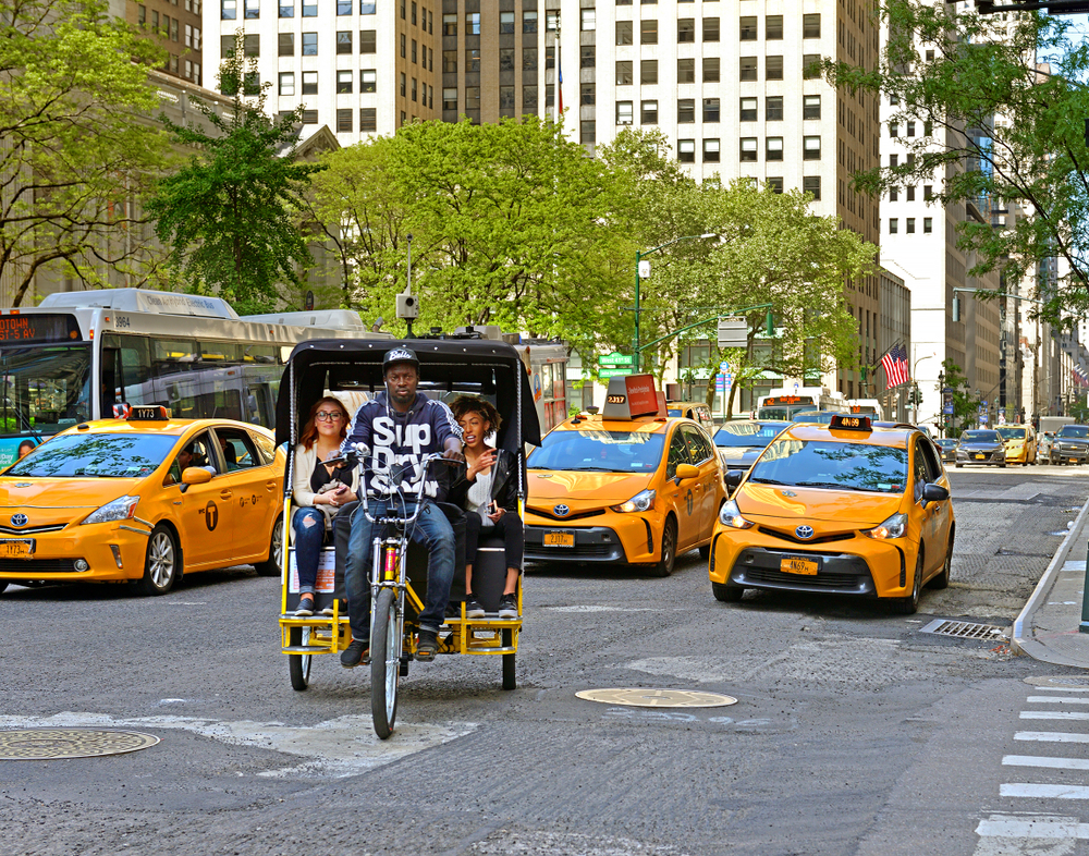 People riding on the back of a rickshaw pedicab for a guide titled Is New York City Safe to Visit