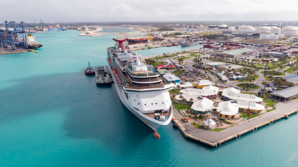 A cruise ship docked on a pier in the Grand Bahama with emerald waters and several hotels are near the pier, a piece on a guide on how many islands are in the Bahamas.