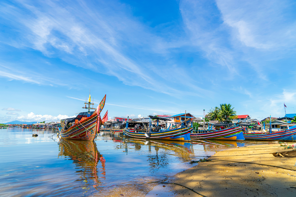 Photo of several colorful boats on the water in one of the Thai areas to avoid, the Narathiwat Province