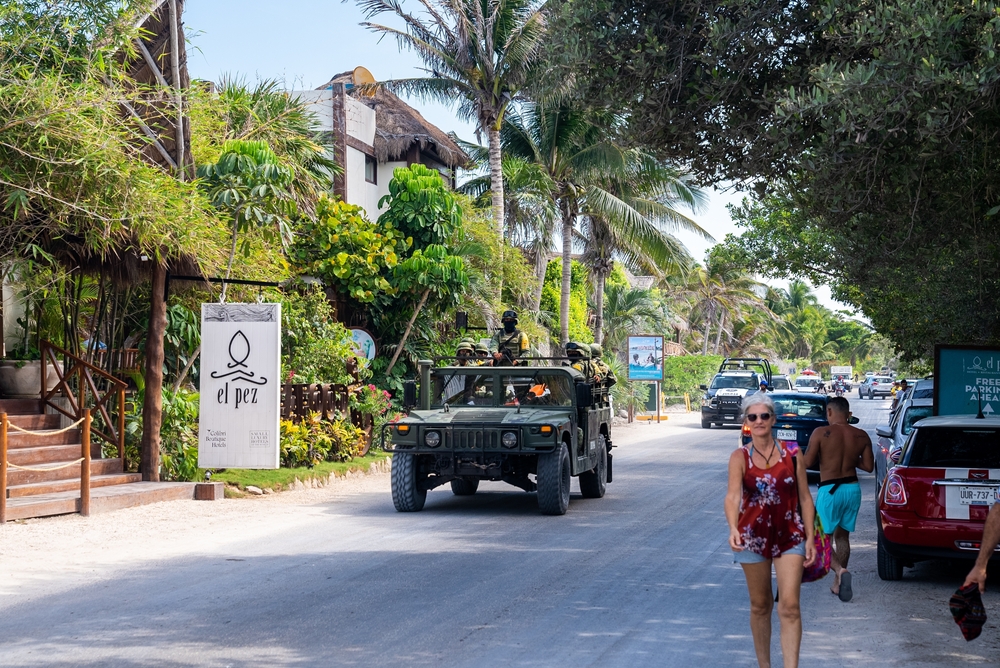 Humvee with a bed-mounted machine gun making its way along the main strip with tourists walking along the shops