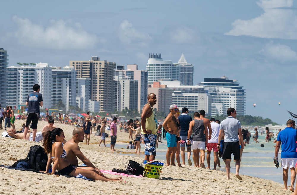 Crowded beach in Miami pictured on a clear summer day with people mulling about and enjoying the water