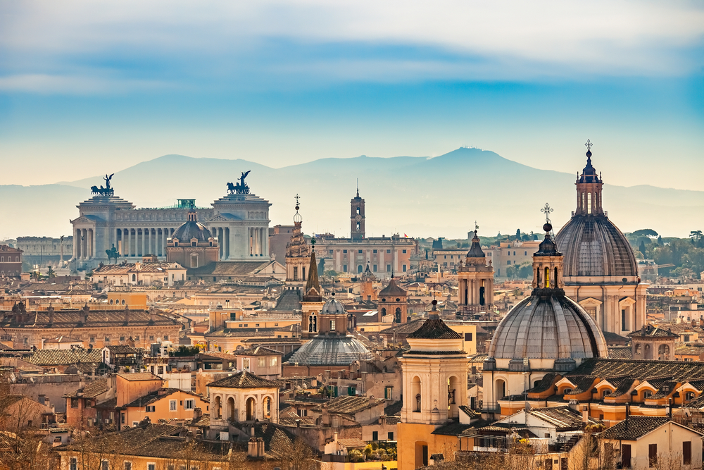 Aerial shot of Rome from Castel Sant'Angelo during a hazy day with mountains in the distance, showing why Rome is one of the top cities to visit in Italy