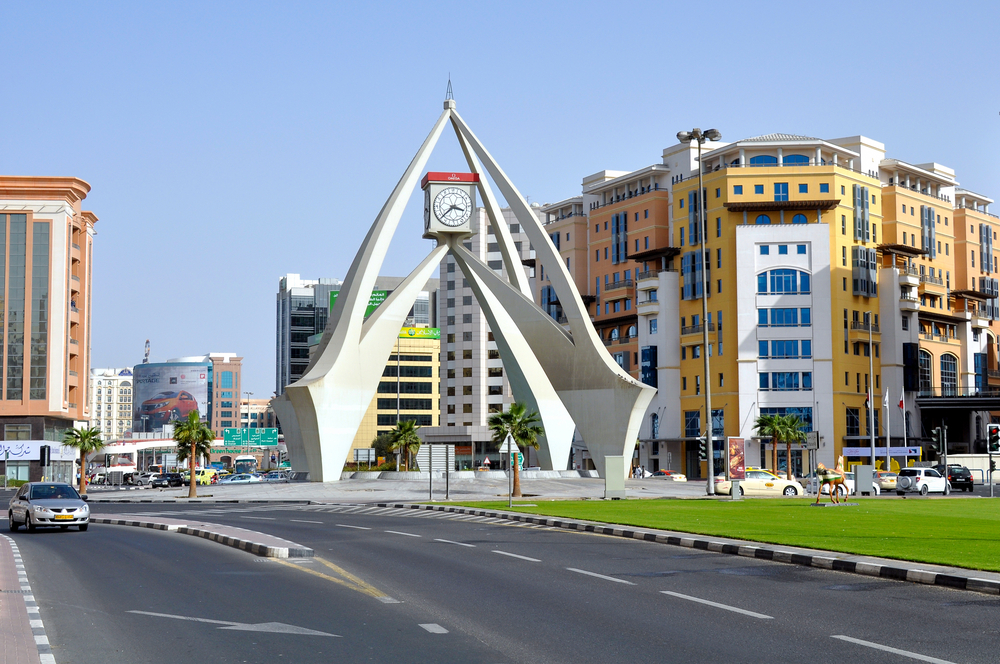 Photo of a giant clock tower above a roundabout on a road in Deira, one of the best places to avoid in Dubai