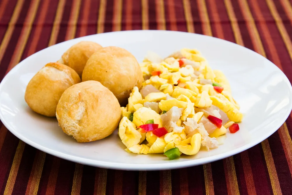 A serving of a Caribbean food names Ackee and Saltfish, on white plate.