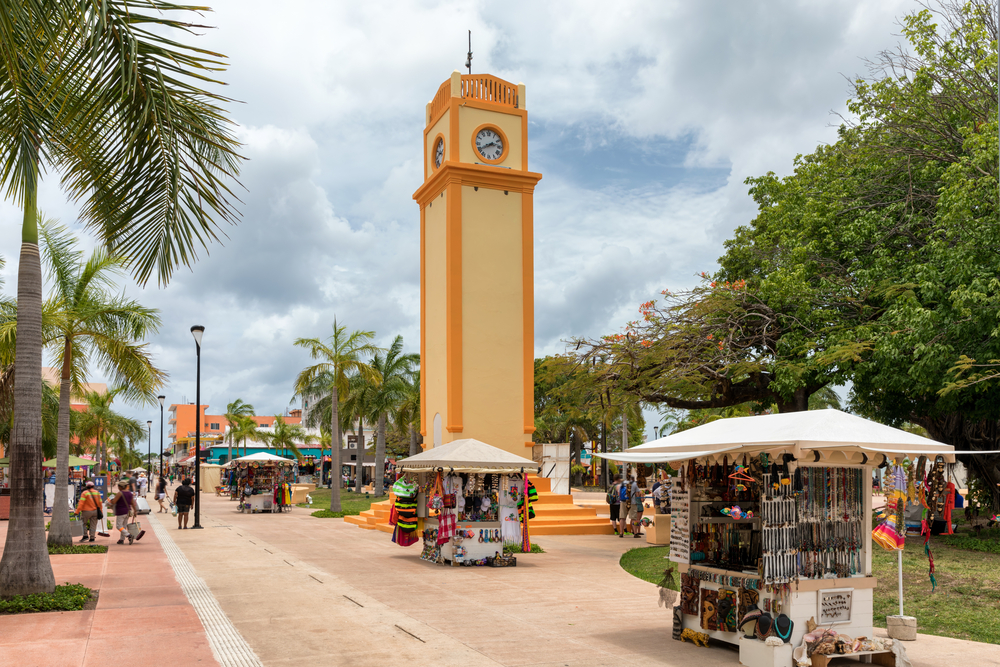 To illustrate that Cozumel is safe to visit, a clocktower towering over small shops in Cozumel