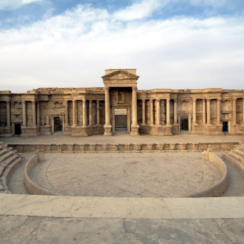 a historical structure with tall columns and an area that looks like an amphitheatre, seen during the best time to visit Syria.
