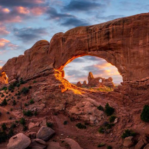an arching rock formation highlighted by the sunset in background during one of the best time to visit Utah.