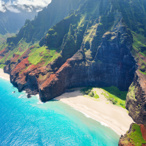 a secluded beach hidden on the side of mountains, the sand is white and the water is calm, photographed during the best time to to visit Kauai.
