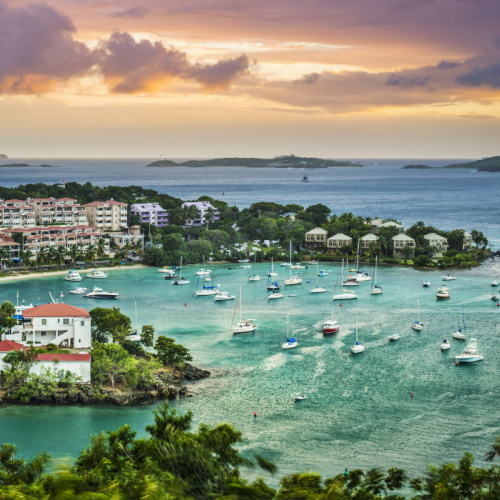 a busy sunset of the best time to visit Saint Thomas, where many ships are sailing in an area of the sea near the coastal area.