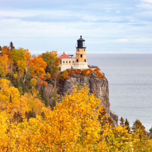 a old lighthouse built on the side of a cliff, seen during the best time to visit Minnesota in an autumn season.