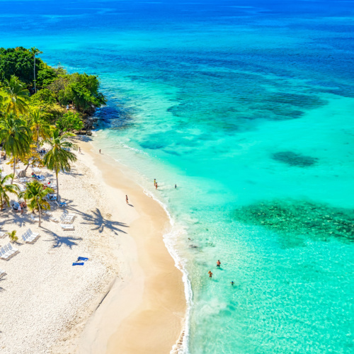 aerial view of a beutiful beach where a fews people can be seen enjoying the waters on a hot afternoon of the best time to visit Dominican Republic.