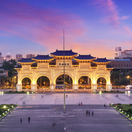 a city building illuminated by lights during dusk of the best time to visit Taiwan, where people can be seen on the square.
