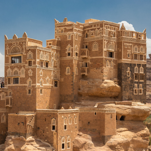 a traditional architecture built integrated to the rocks of a hill on a desert area, seen during the best time to visit Yemen.