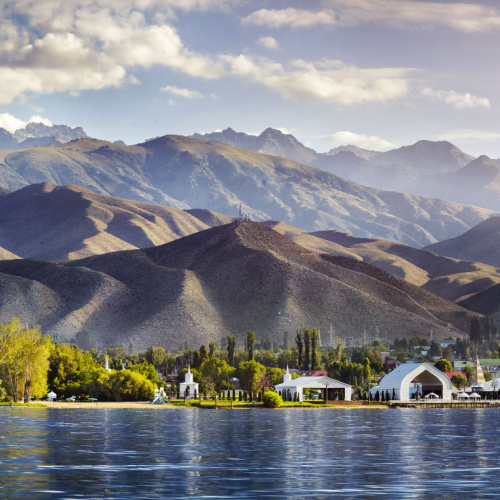 a view from a distance where a town can be seen near the lake, and in background are mountains, seen during an afternoon of the best time to visit Kyrgyzstan.