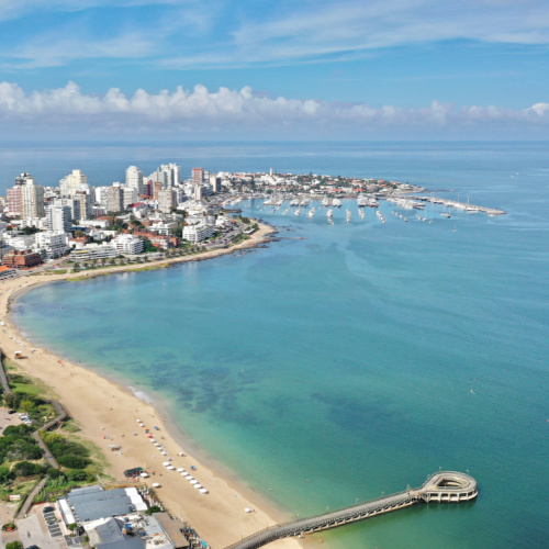 a coastal area where buildings can be seen occupying the center of the land, and the surrounding waters are clear and calm, seen during one of the best time to visit Uruguay.