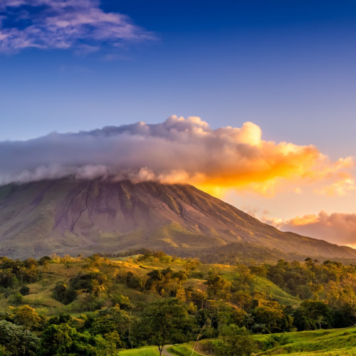 the top of a volcano where its peak is fully covered with clouds, during a sunset of the best time to visit Costa Rica.