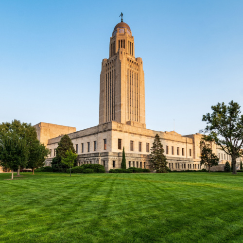 a capitol building with a vast green field during a late afternoon of the best time to visit Nebraska.