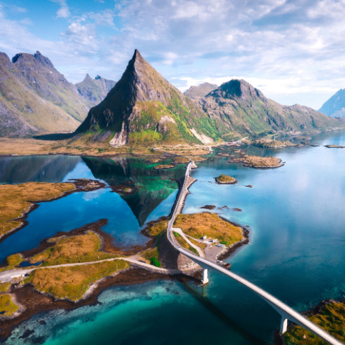 photographed during the best time to visit Norway, where a long bridge is crossing a wide river towards a mountainous area.