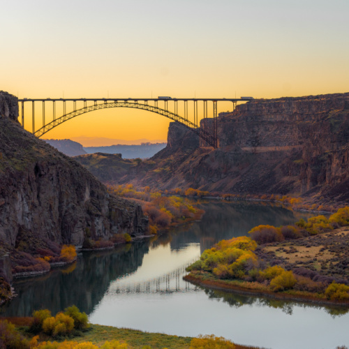 a bridge crossing two cliffs during a sunset of the best time to visit Idaho.