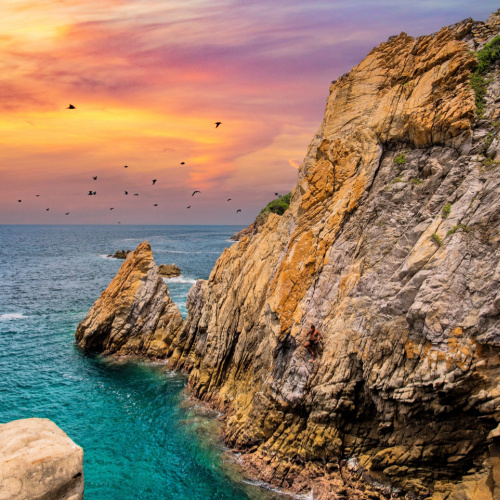 large rocks and at the bottom are clear waters during a sunset of the best time to visit Acapulco.