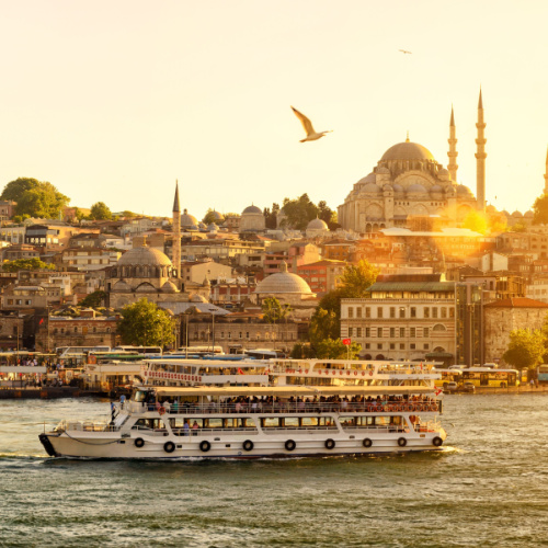 a view during a sunset if the best time to visit Turkey, where a ferry can be seen passing through a rich town with old and historical structures.