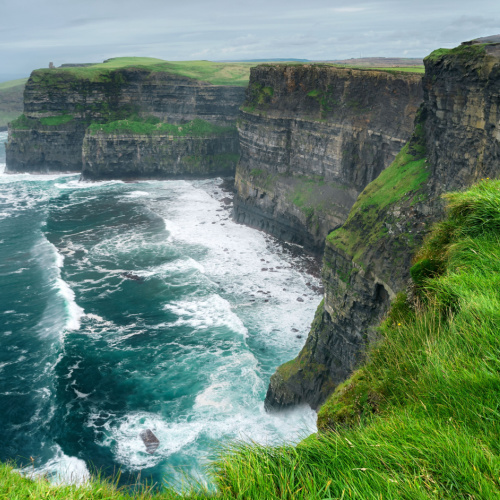 spectacular view of cliffs on an overcast day of the best time to visit Ireland, and at the bottom are foams due to crashing waves.