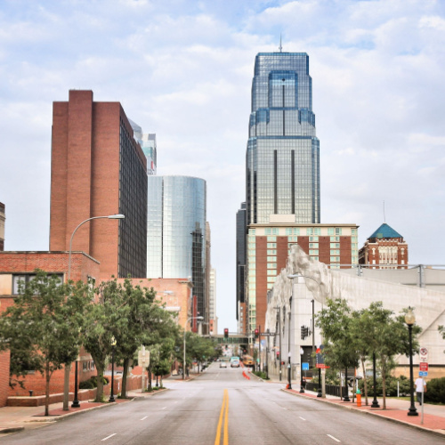 a view from the middle of the street where the modern buildings are seen on each side of a progressive city, photographed during the best time to visit Kansas.