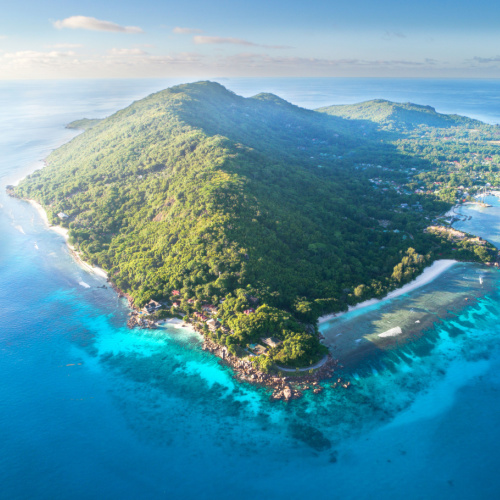 aerial view of an island filled with trees and the surrounding waters are emerald and clear, seen during the best time to visit Seychelles.