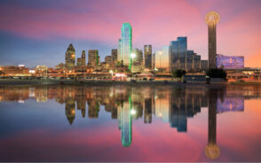 Photo of a pink sky over Dallas, pictured during the best time to visit the city, with the giant ball structure towering over the downtown skyline