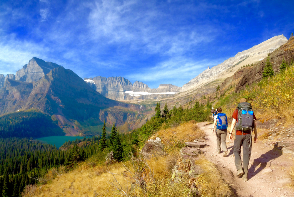 A man and a woman hiking along a picturesque trail in Glacier National Park in the summer, the overall best time to visit Montana